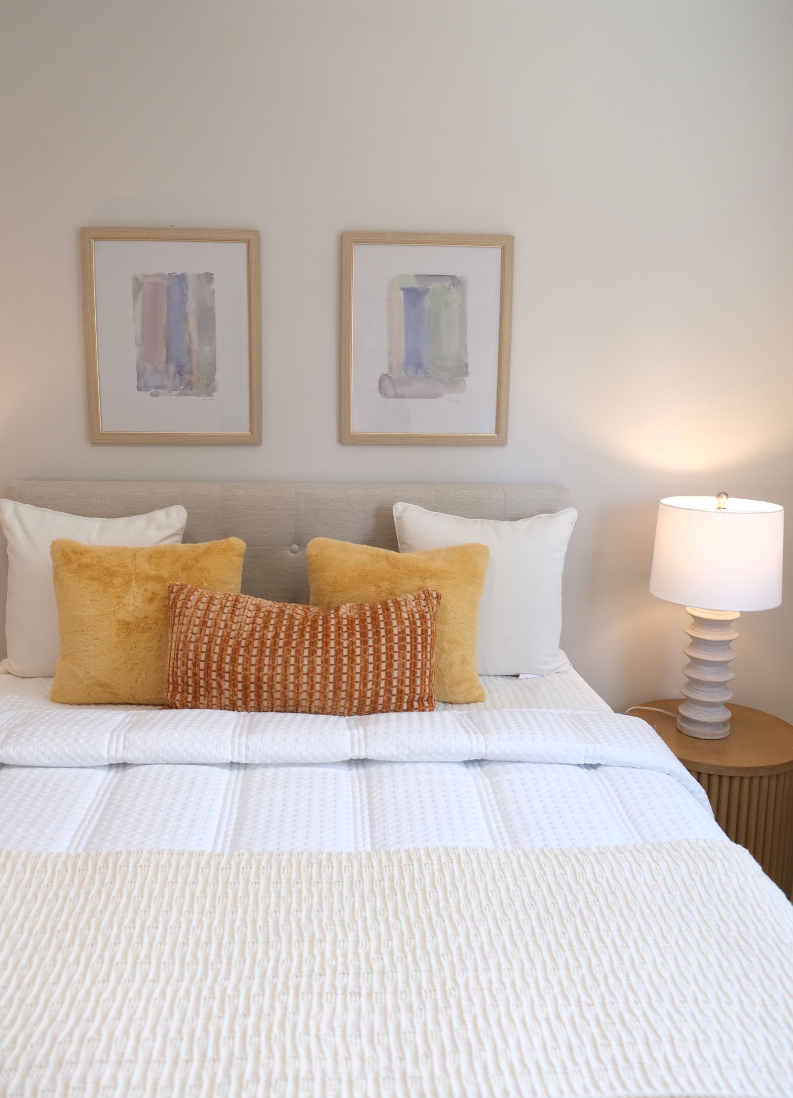 A made bed with neutral linens in a staged bedroom